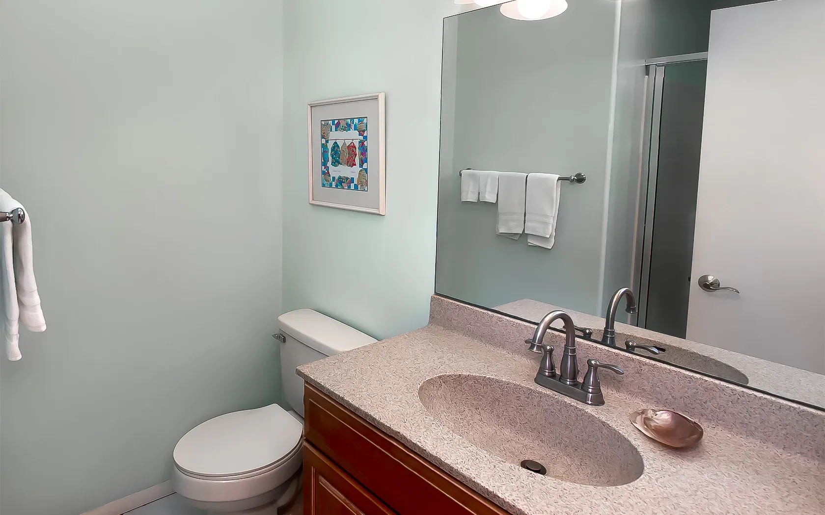 A bathroom with a toilet , sink and mirror.