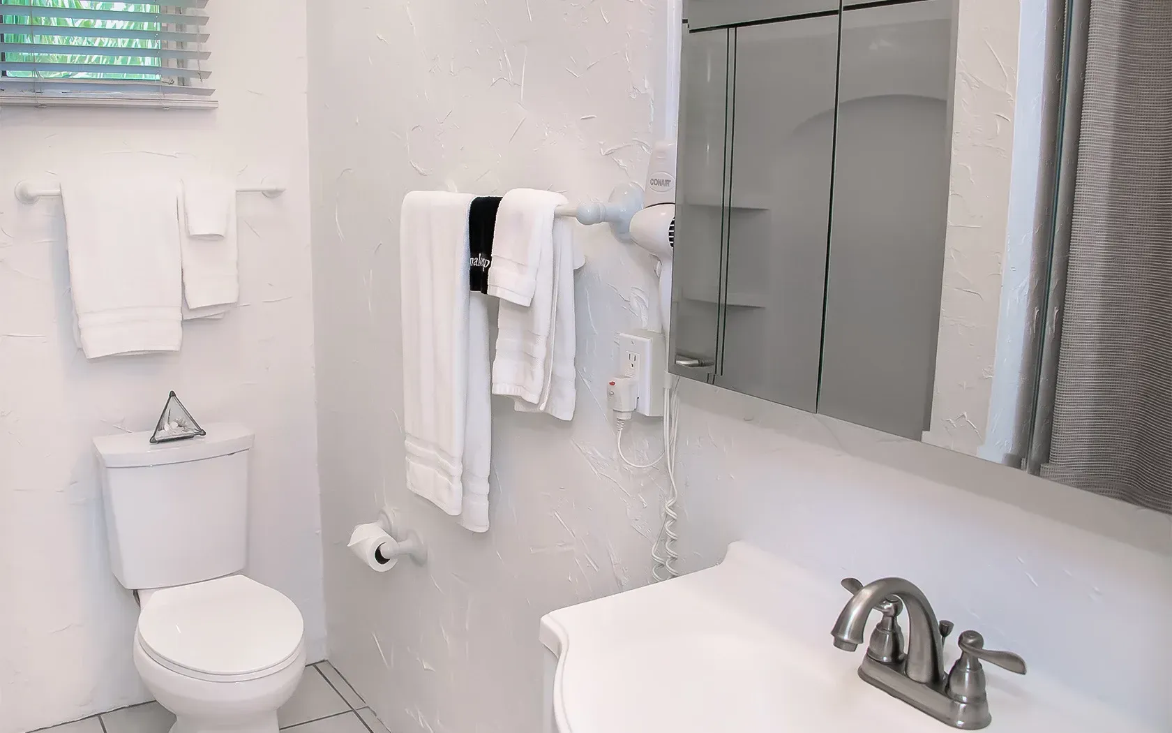 A bathroom with a toilet , sink and mirror.