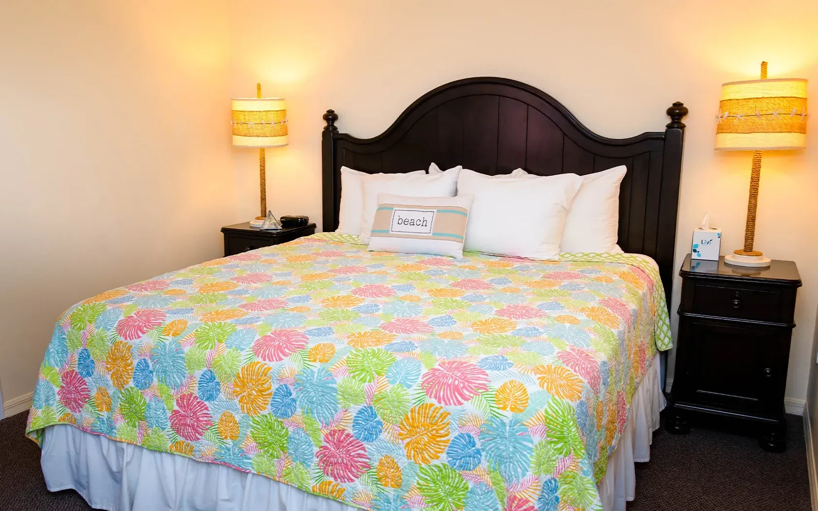 A hotel room with a king size bed and two lamps.