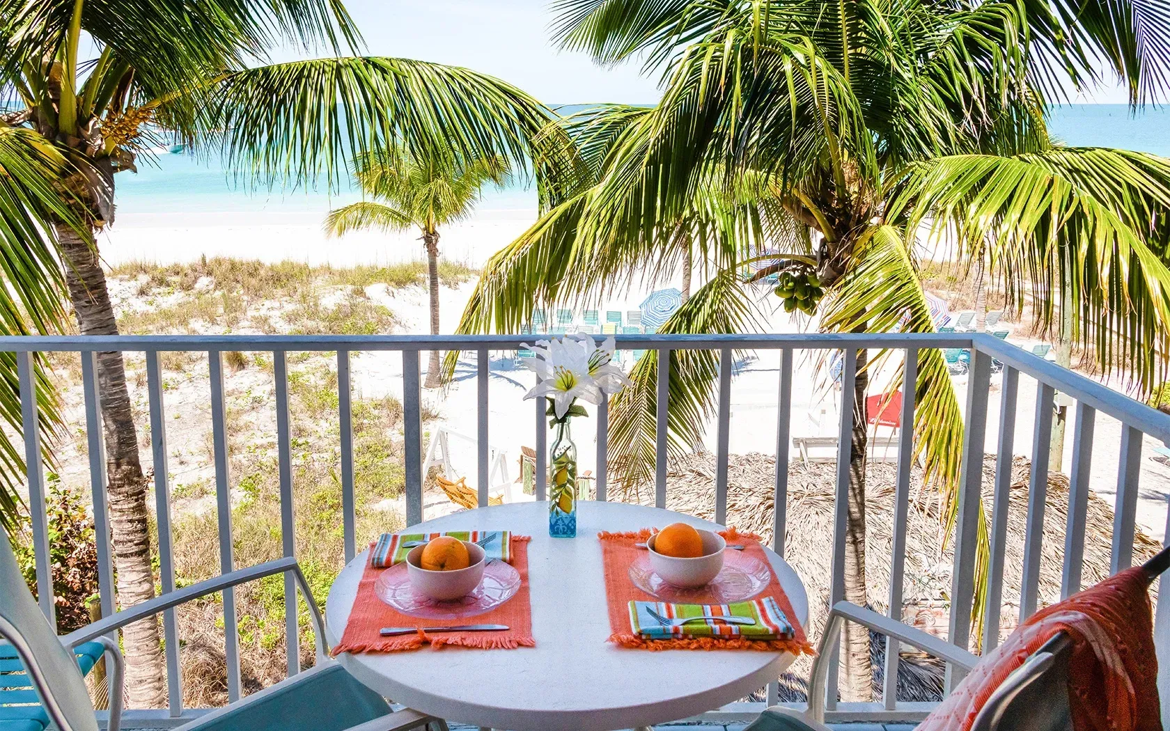 A balcony with a table and chairs overlooking the ocean.