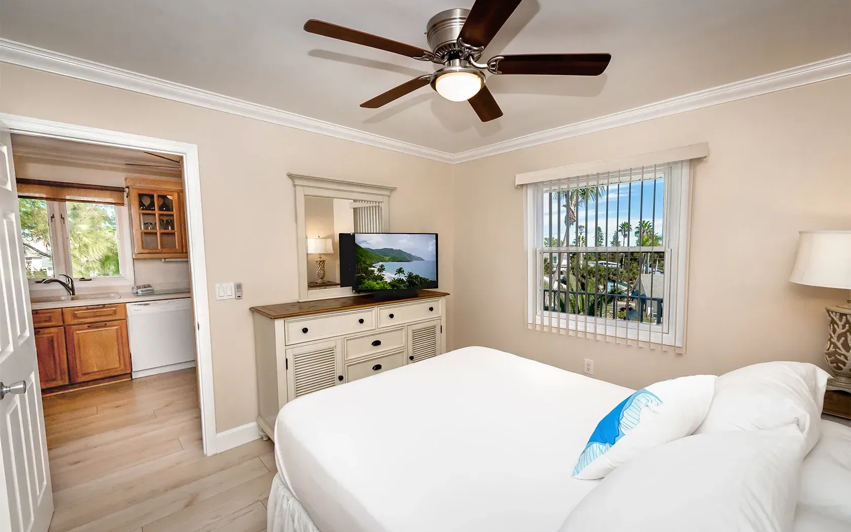 A bedroom with a bed , dresser , television and ceiling fan.