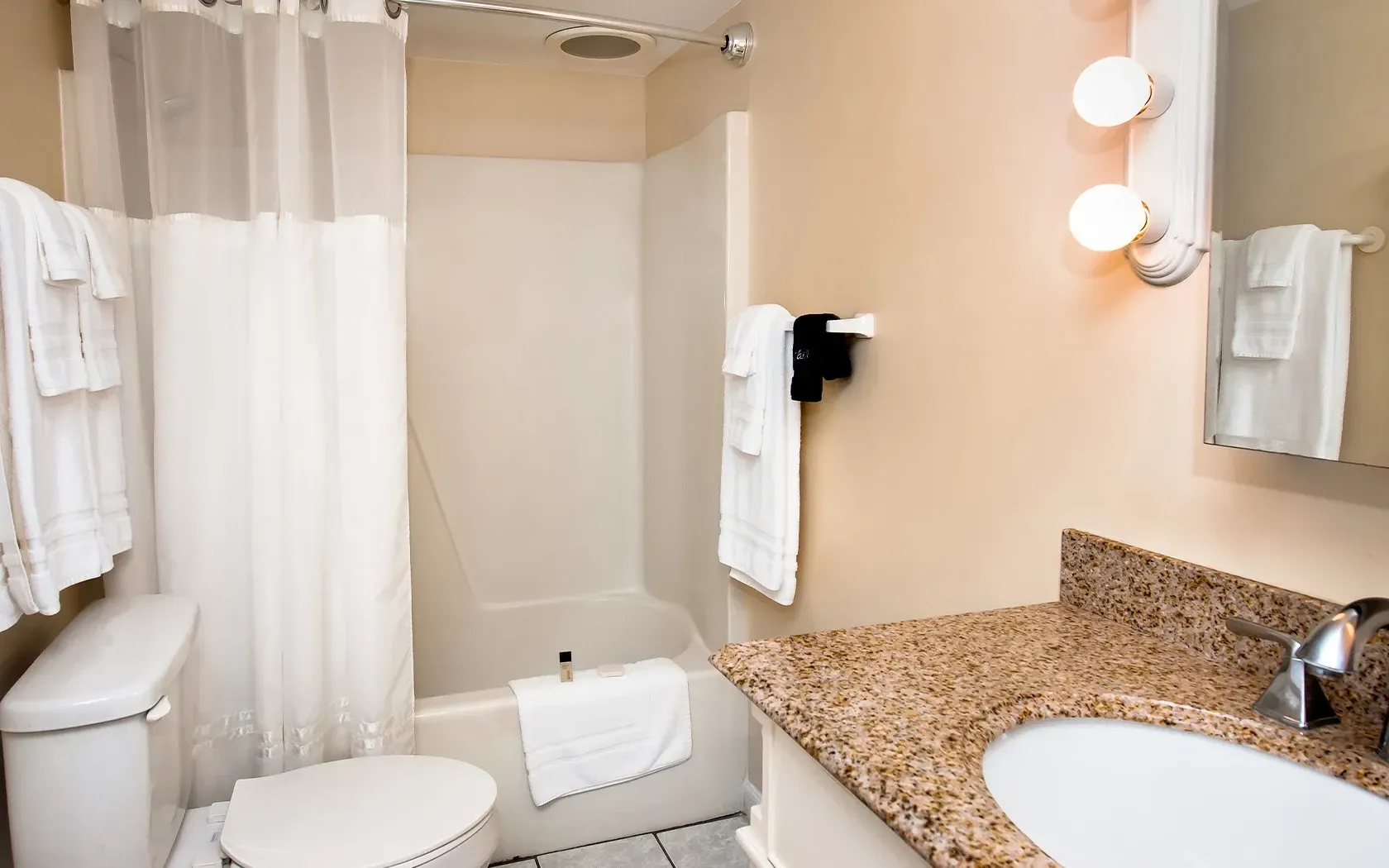 A bathroom with a toilet , sink , bathtub and shower curtain