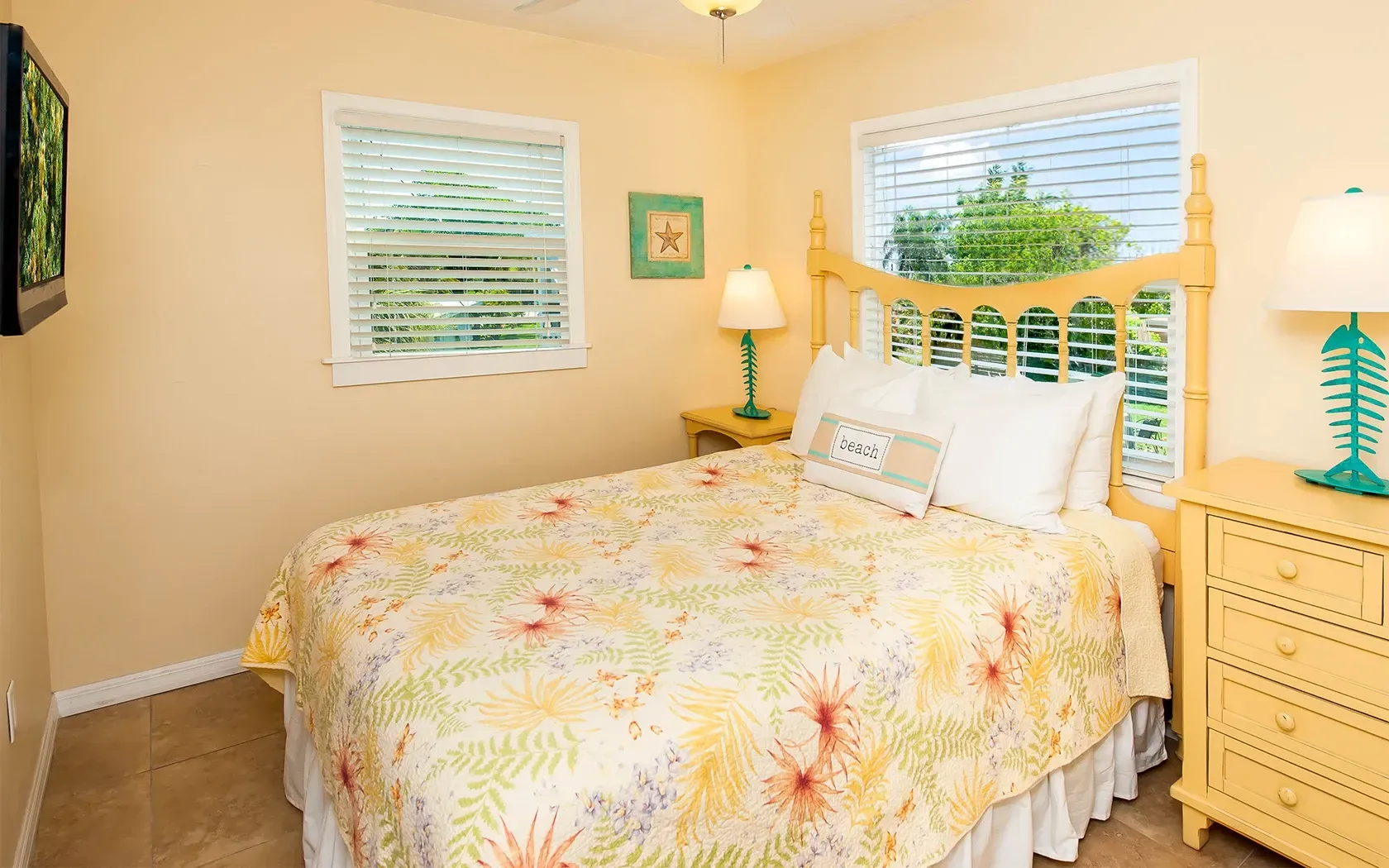 A bedroom with a king size bed , dresser , lamp and television.