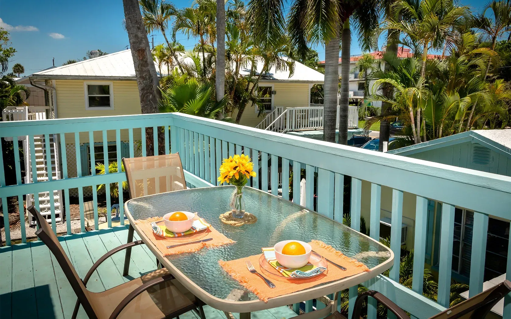 A balcony with a table and chairs and a vase of flowers on it