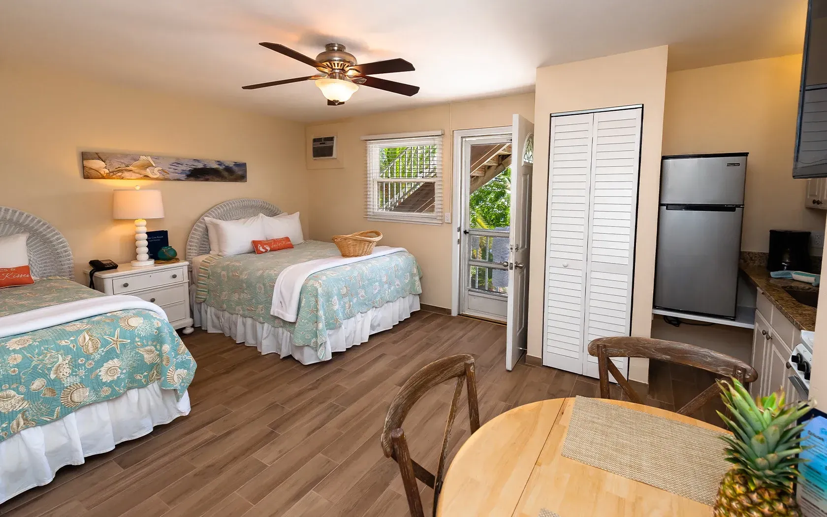 A hotel room with two beds , a table and a refrigerator.