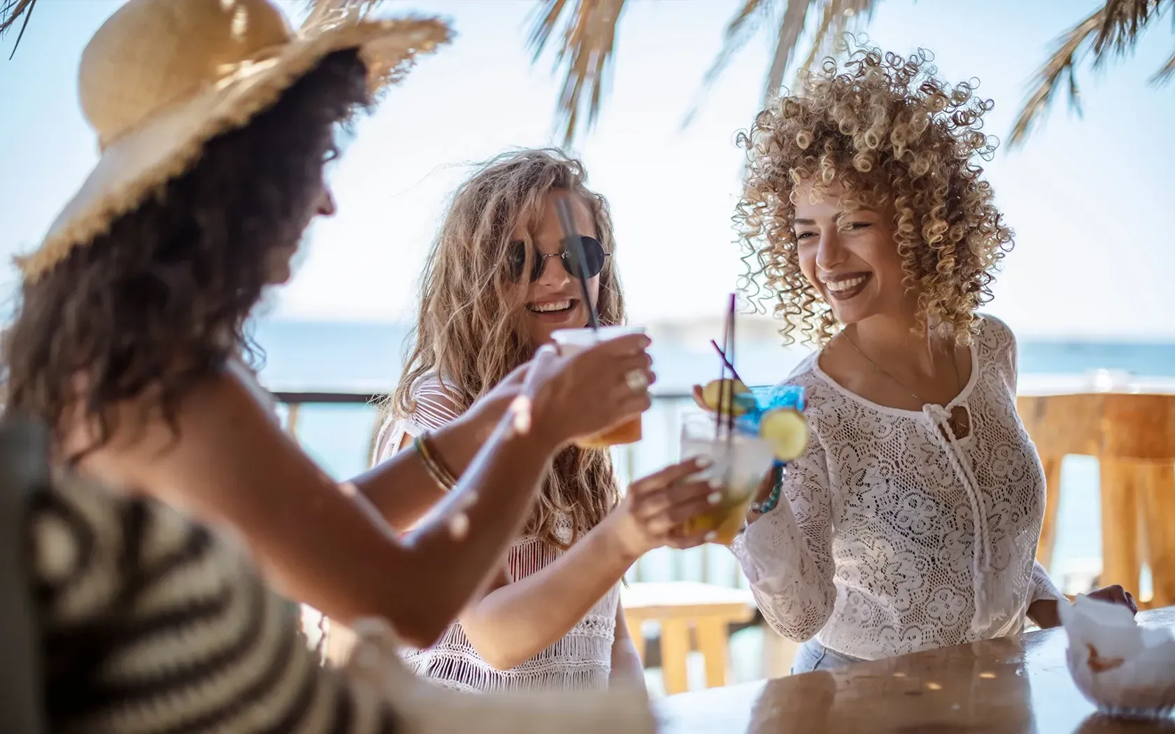 Three women are sitting at a table drinking cocktails.