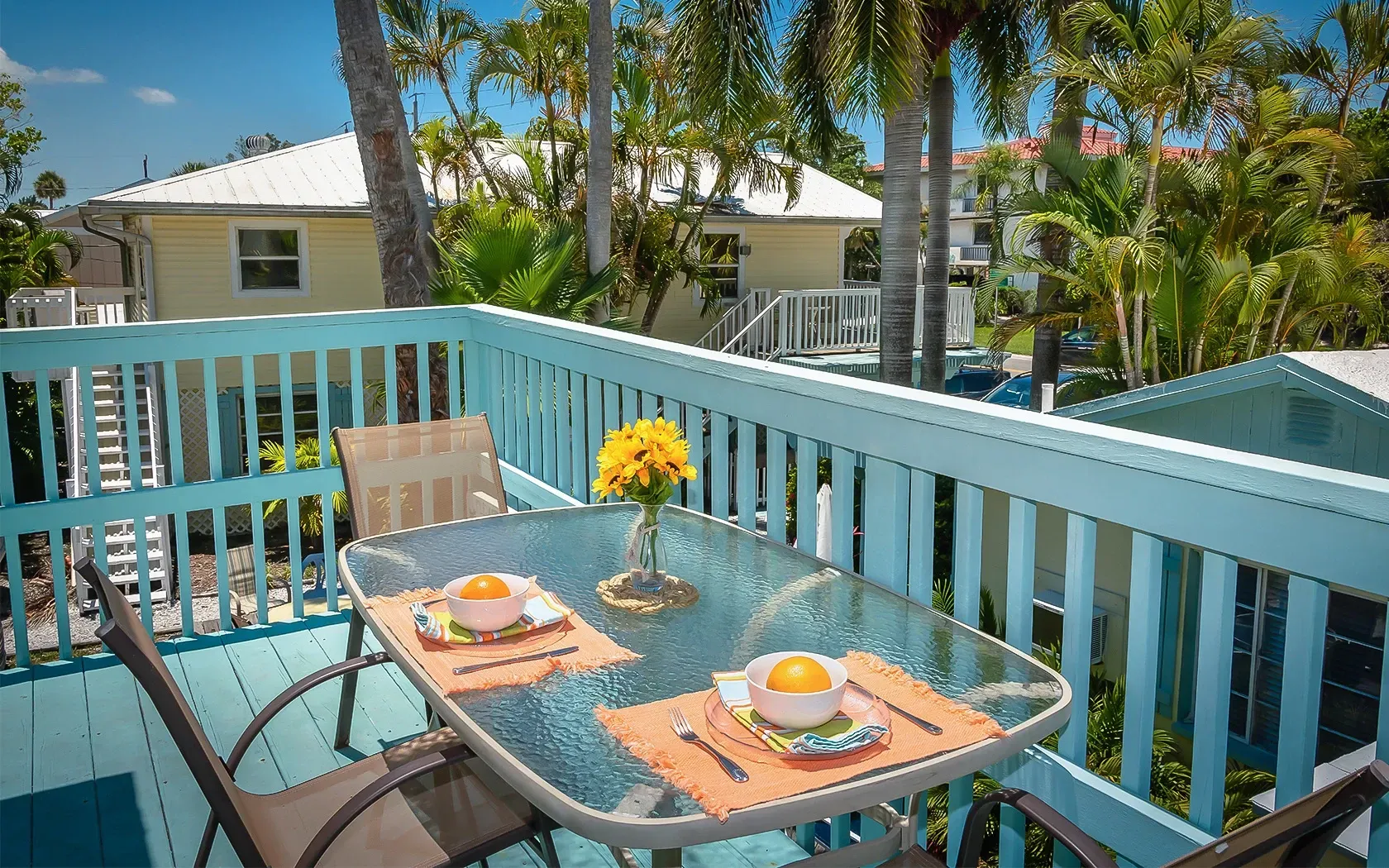 There is a table and chairs on the deck of a house.