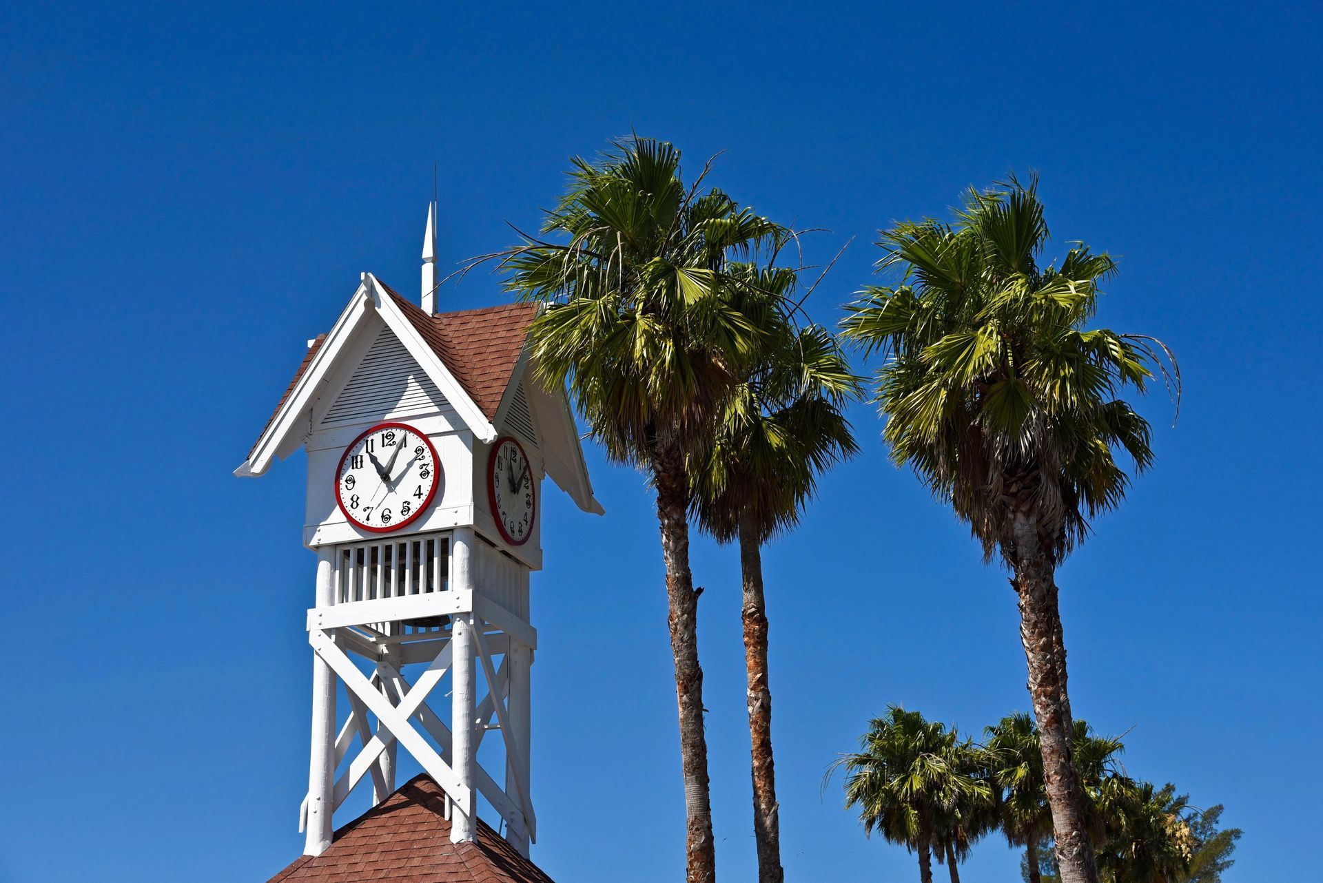 A clock tower with palm trees in the background