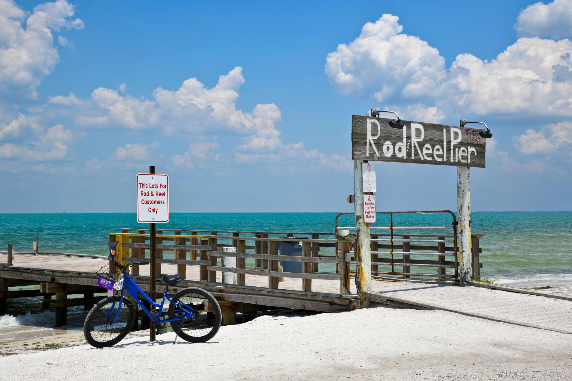 A bicycle is parked in front of a sign that says rod reel pier