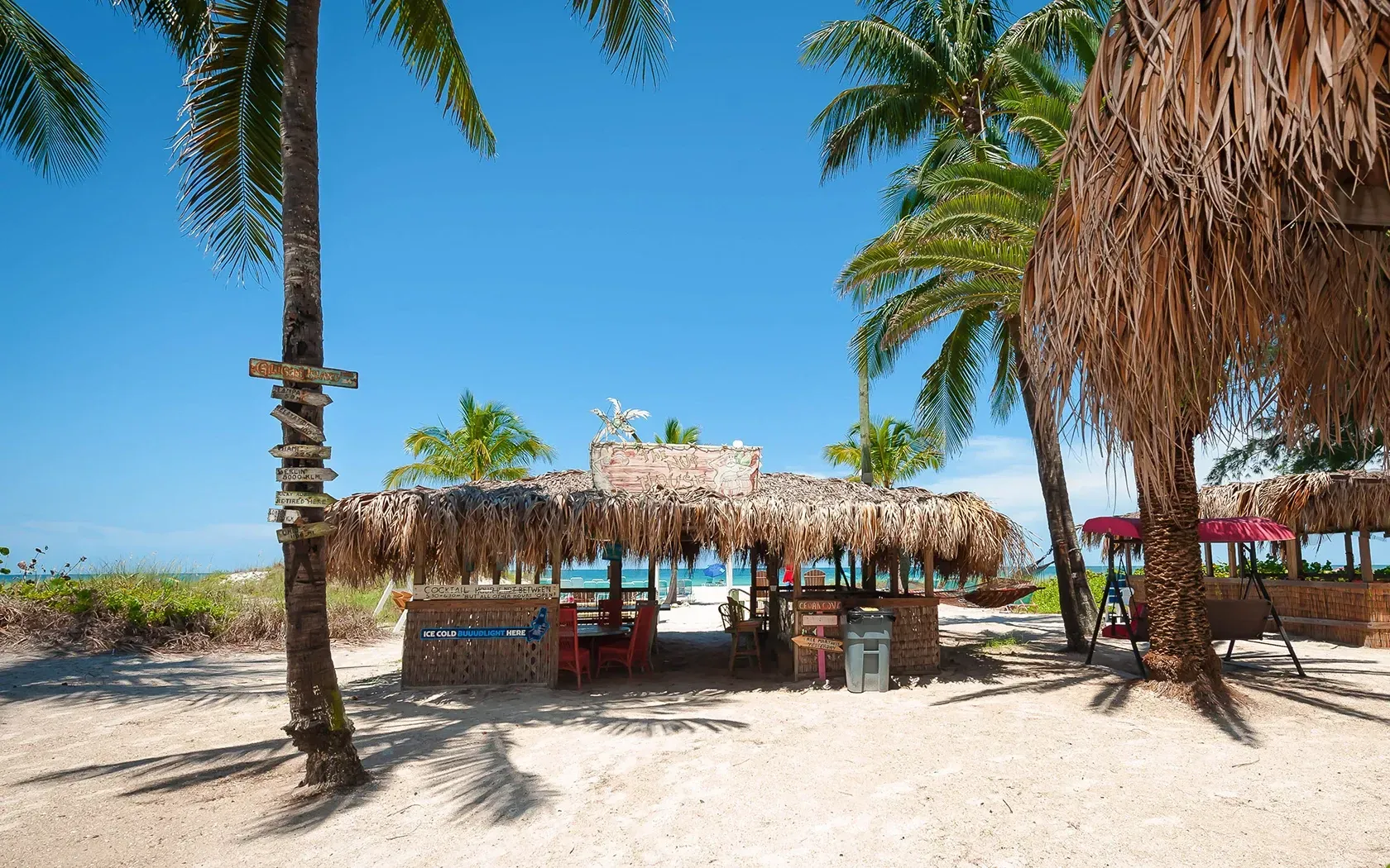 A thatched hut on a beach with palm trees
