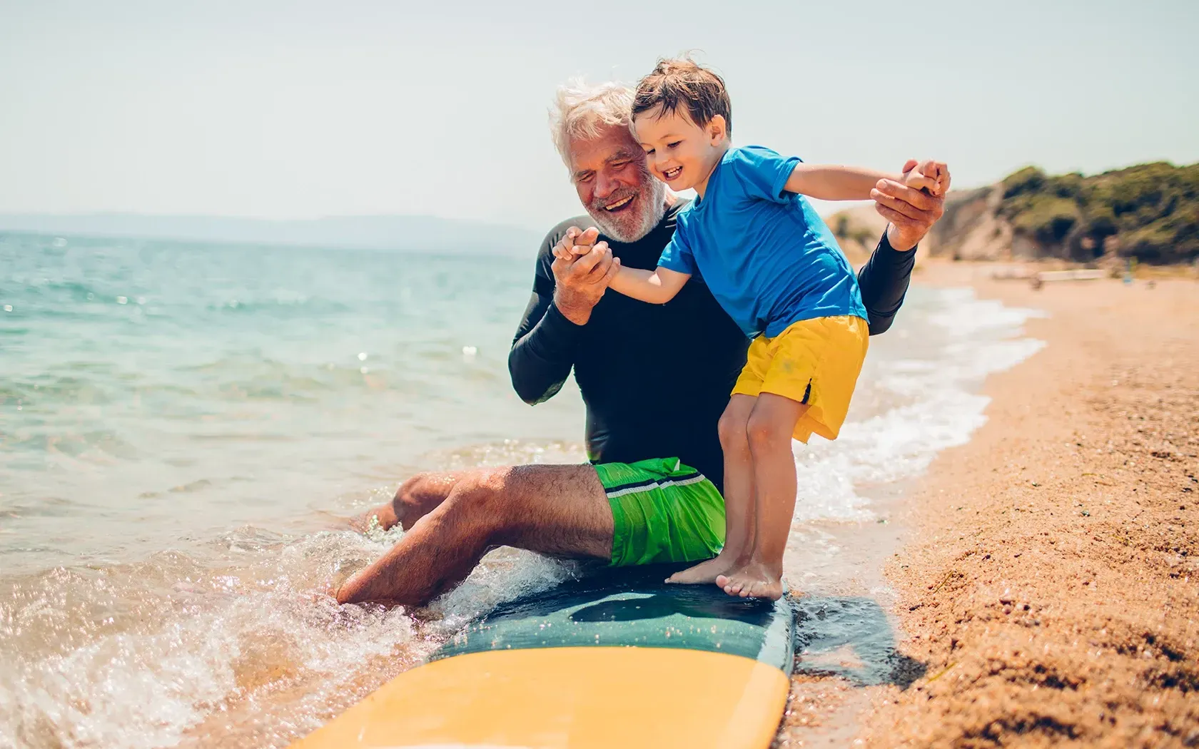 A man and a boy are sitting on a surfboard in the ocean.