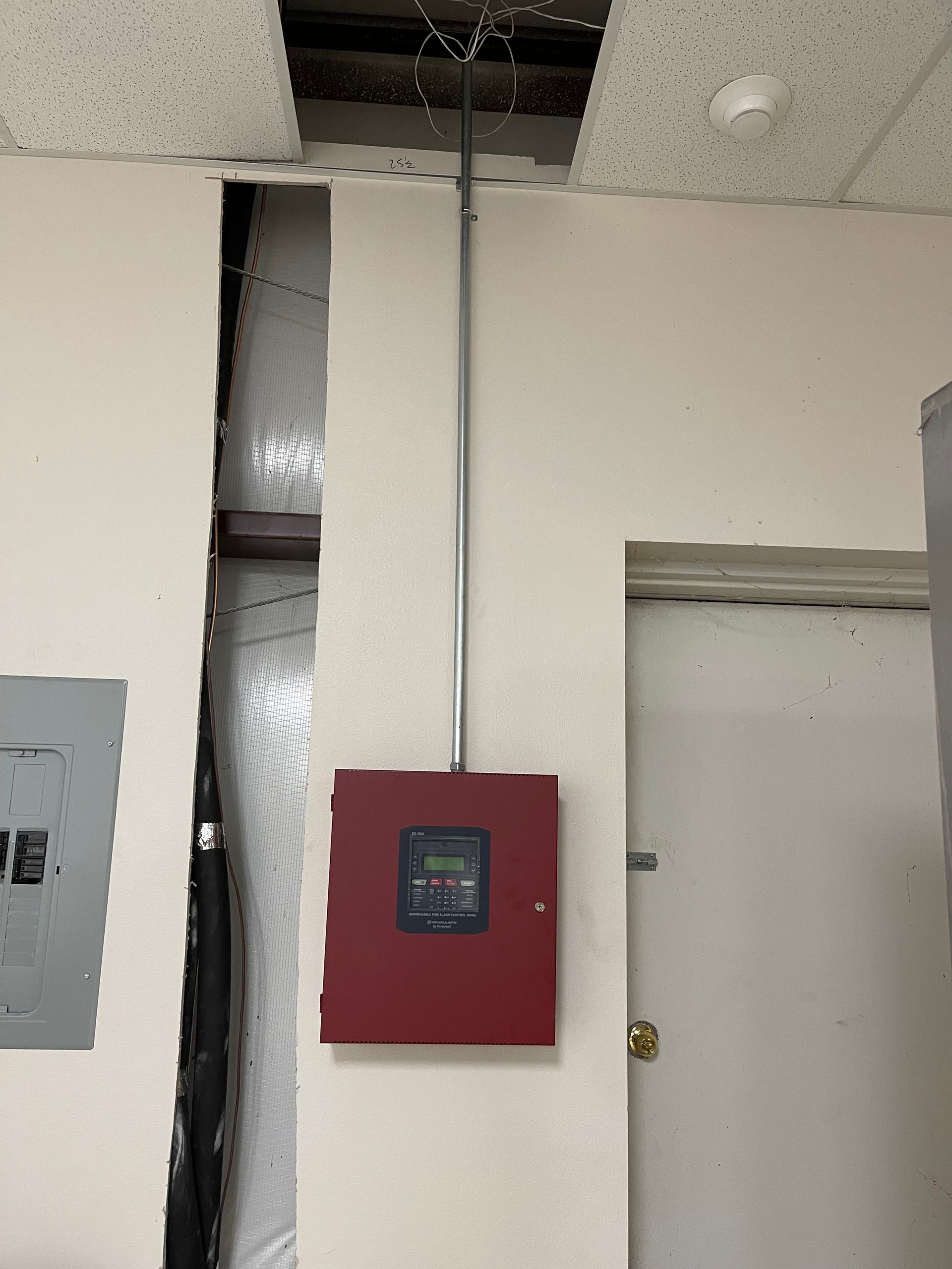 Red fire alarm system components mounted on a white wall.