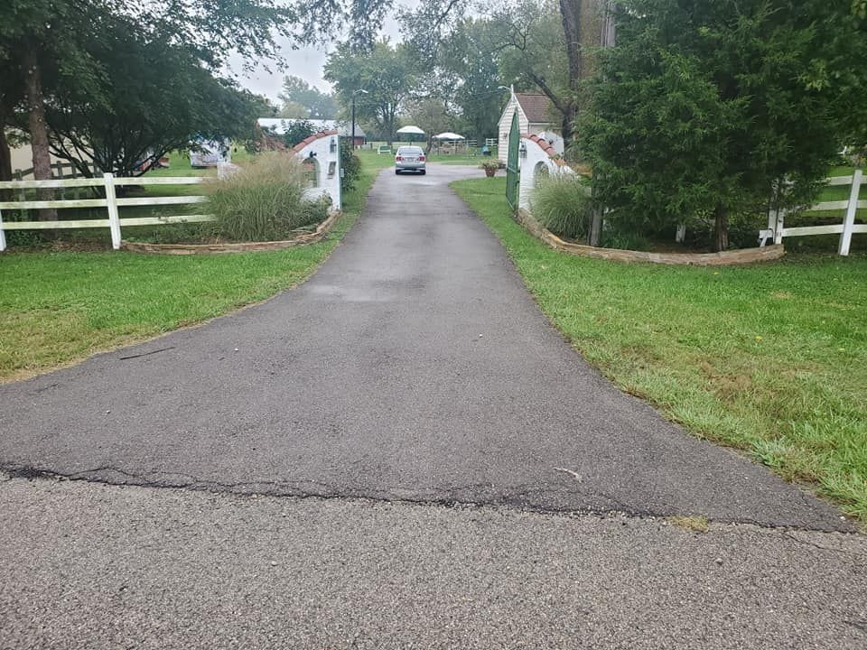 A car is driving down a road next to a white fence.