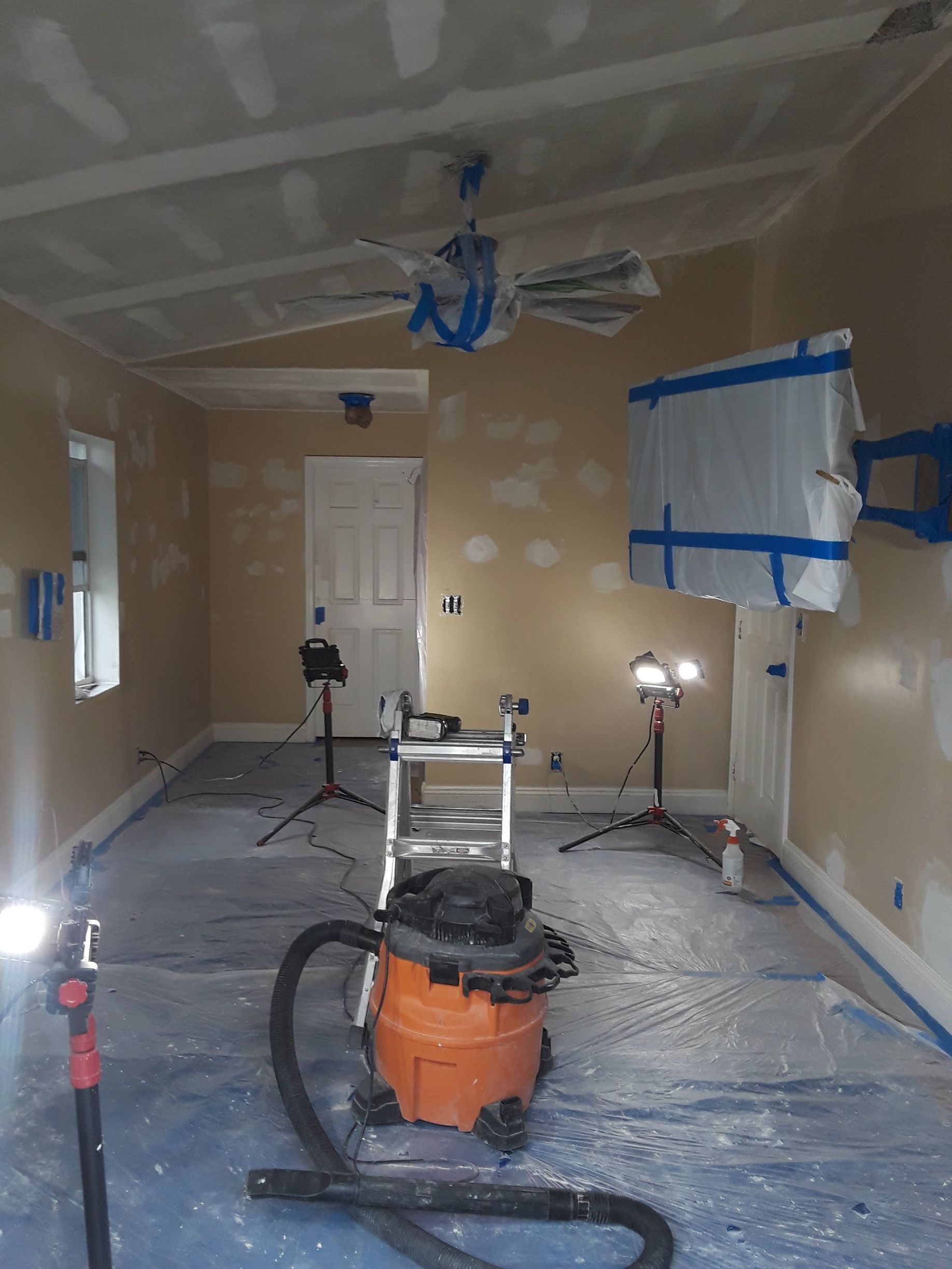 A vacuum cleaner is sitting in a room with a ceiling fan.