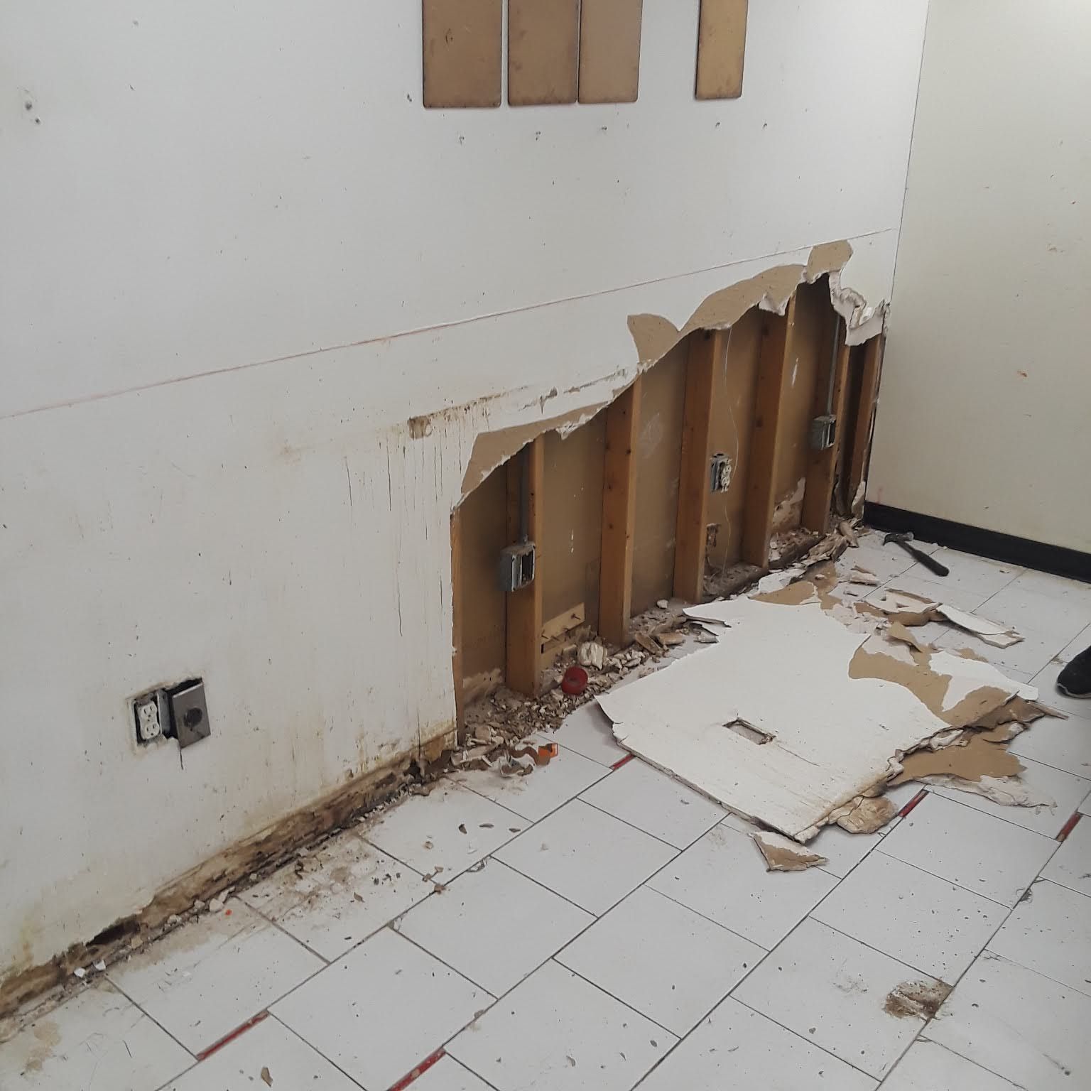 A room with a hole in the wall and a piece of cardboard on the floor