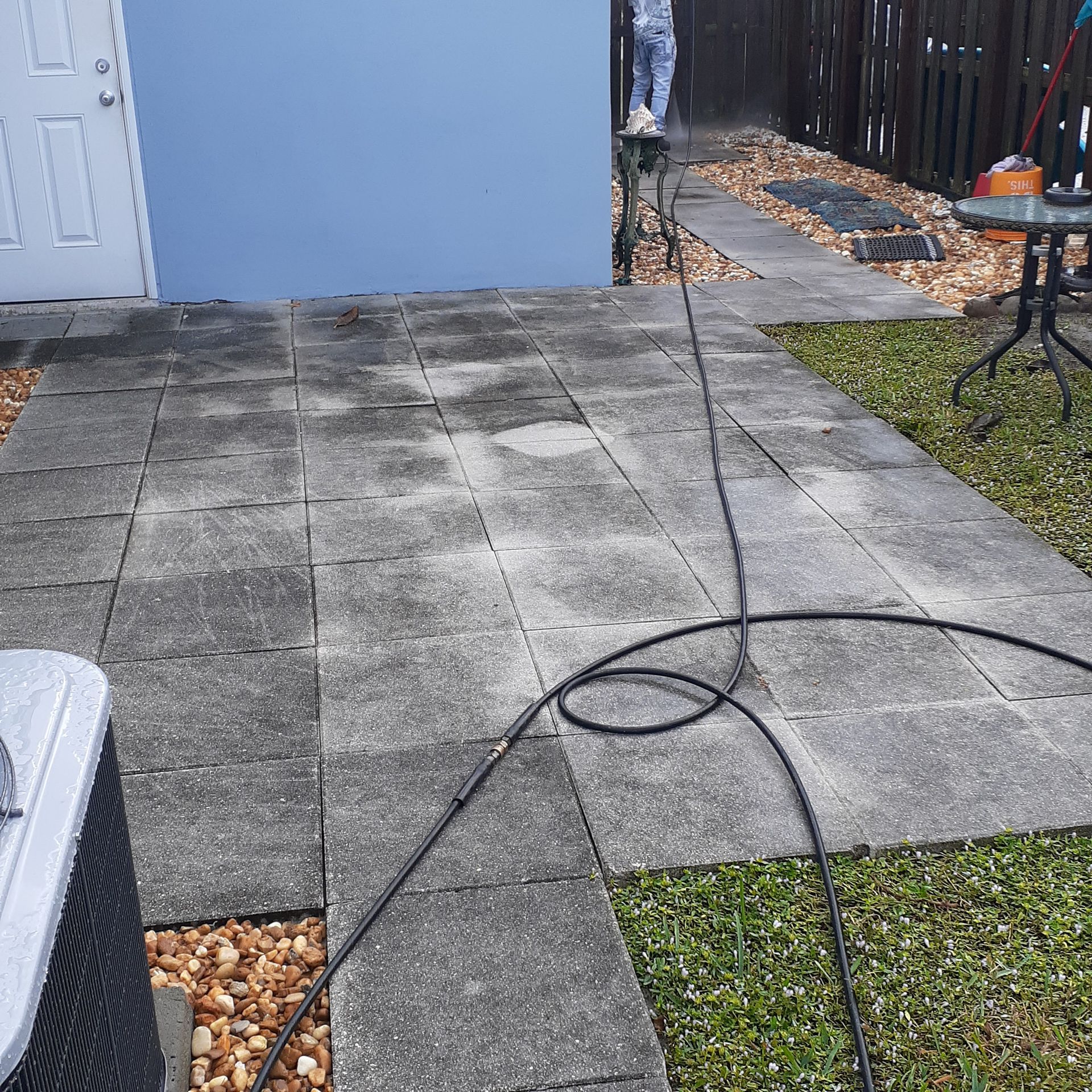 A person is cleaning a patio with a pressure washer.