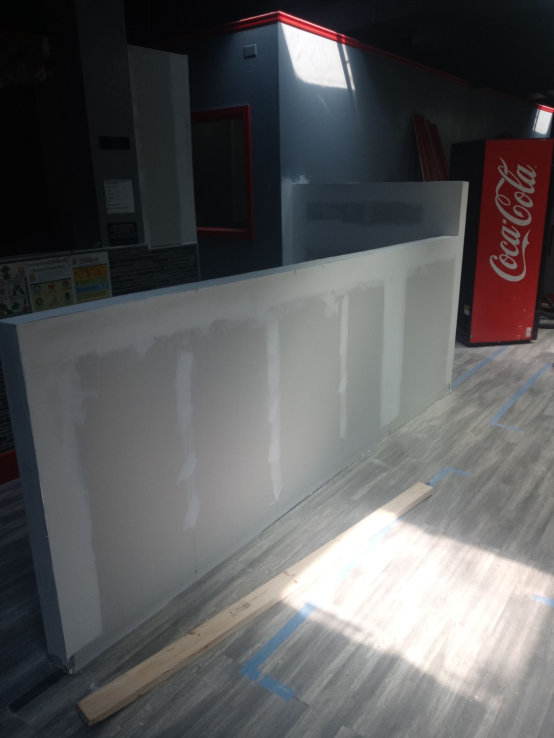 A coca cola vending machine is sitting next to a wall in a room.