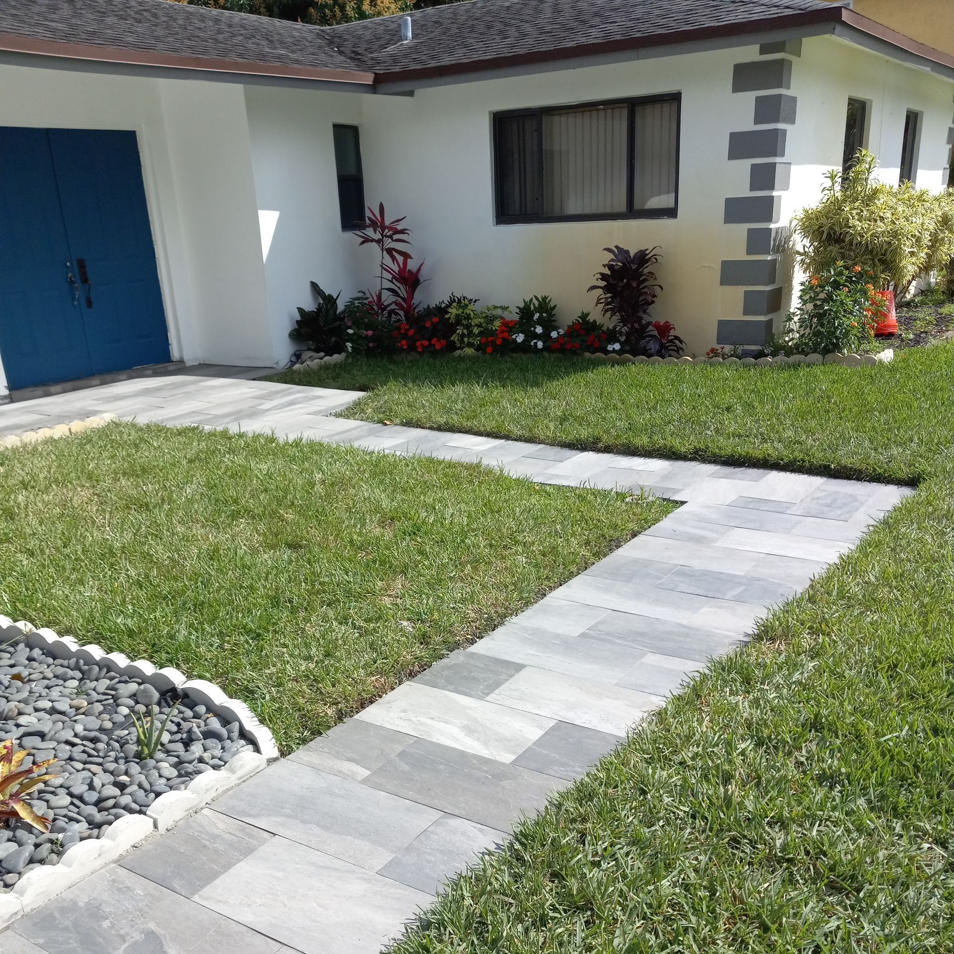 A walkway leading to a white house with a blue door