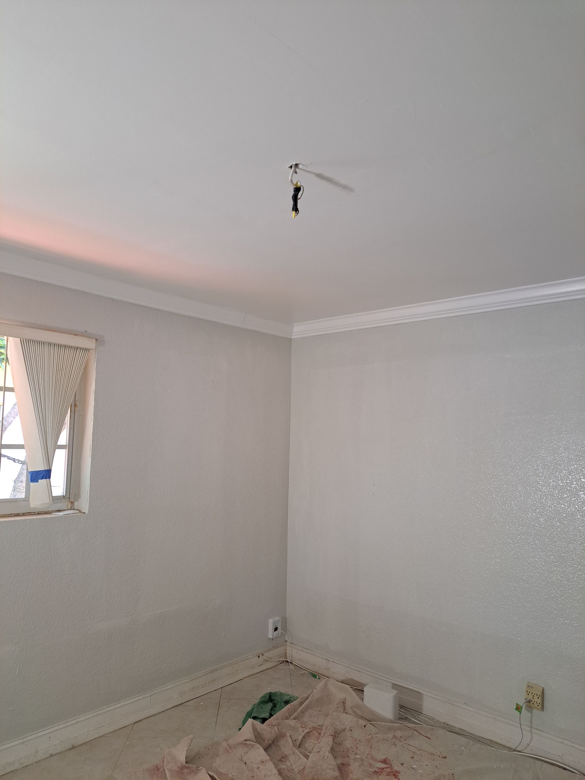 An empty room with a window and a ceiling fan.