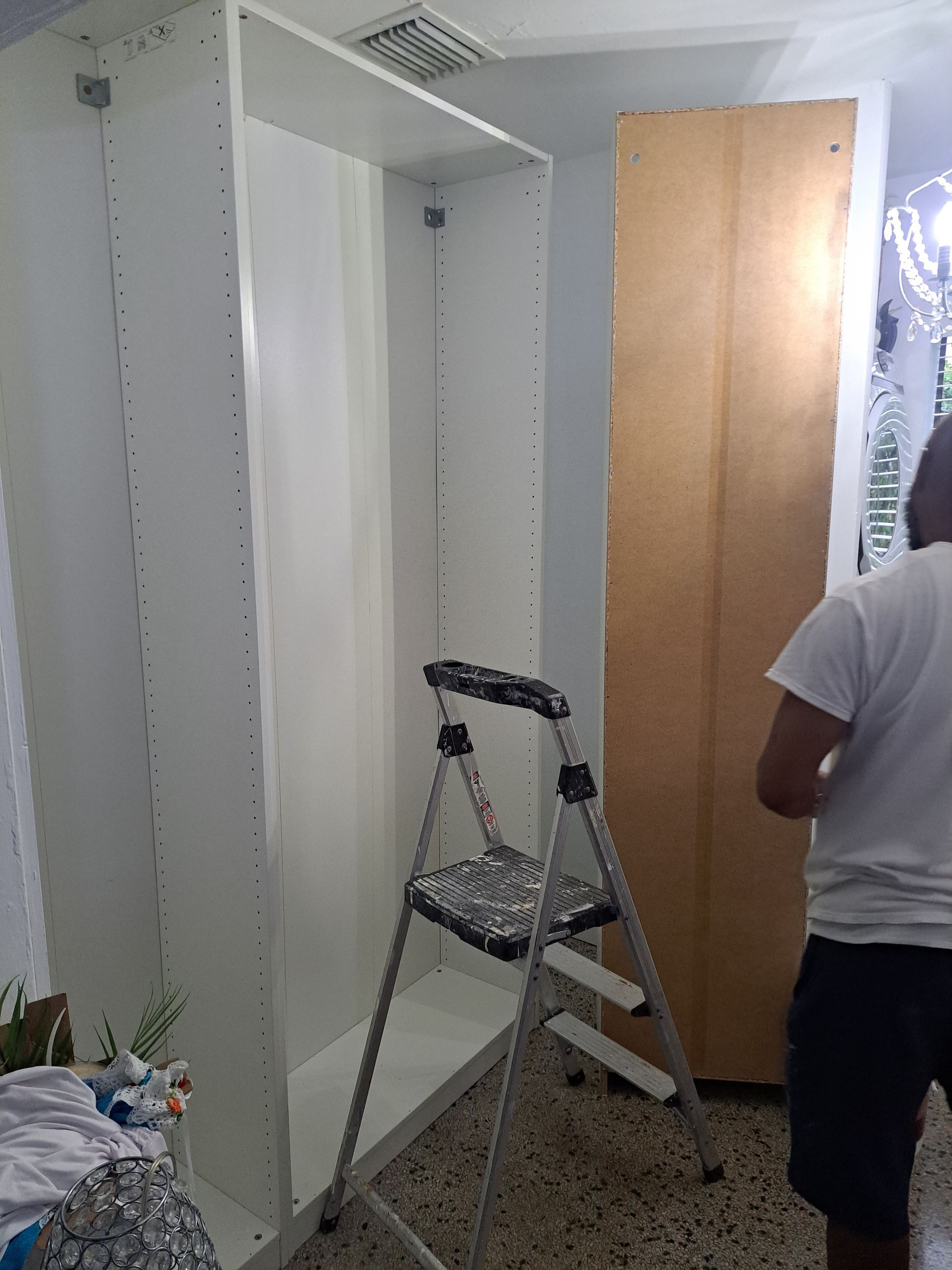A man is standing next to a ladder in front of a wardrobe.