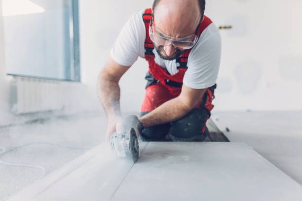 A man is cutting a tile floor with a grinder.