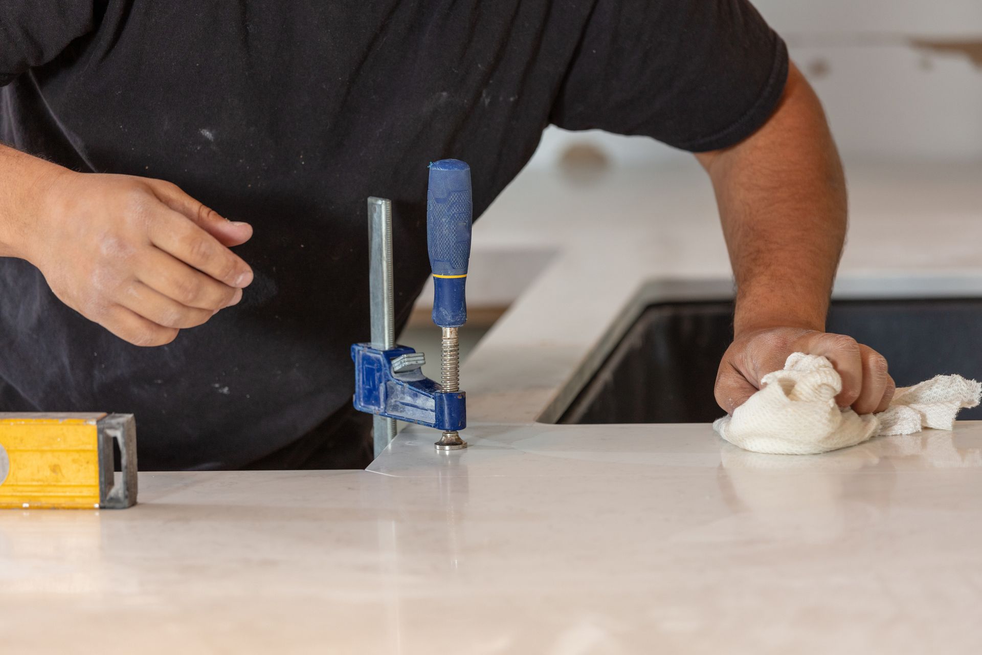 A man is cleaning a counter top with a clamp.