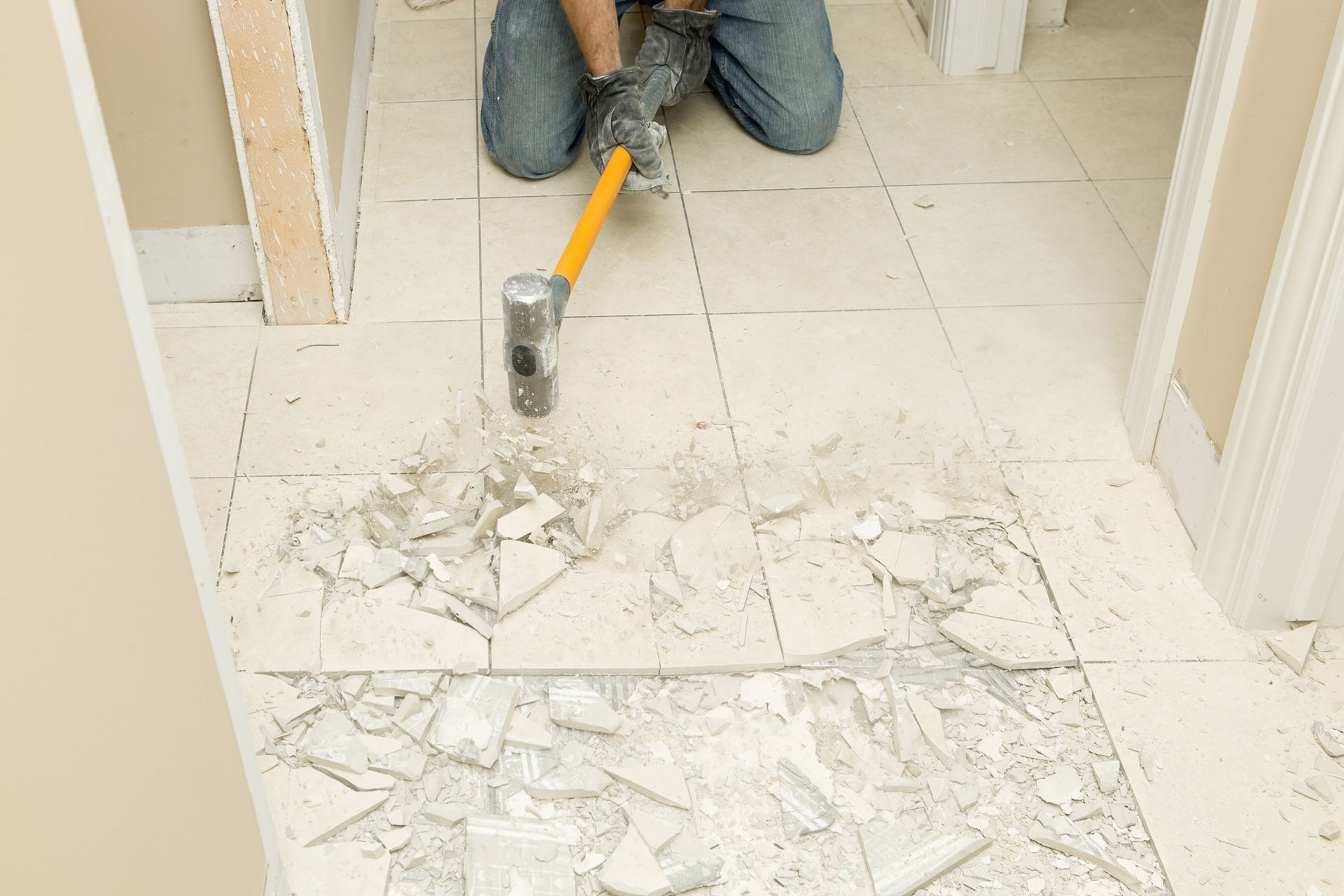A man is kneeling on the floor with a hammer.