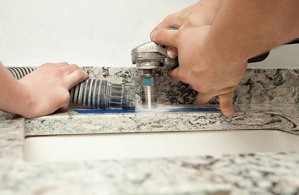 A person is using a vacuum cleaner to clean a bathroom sink.