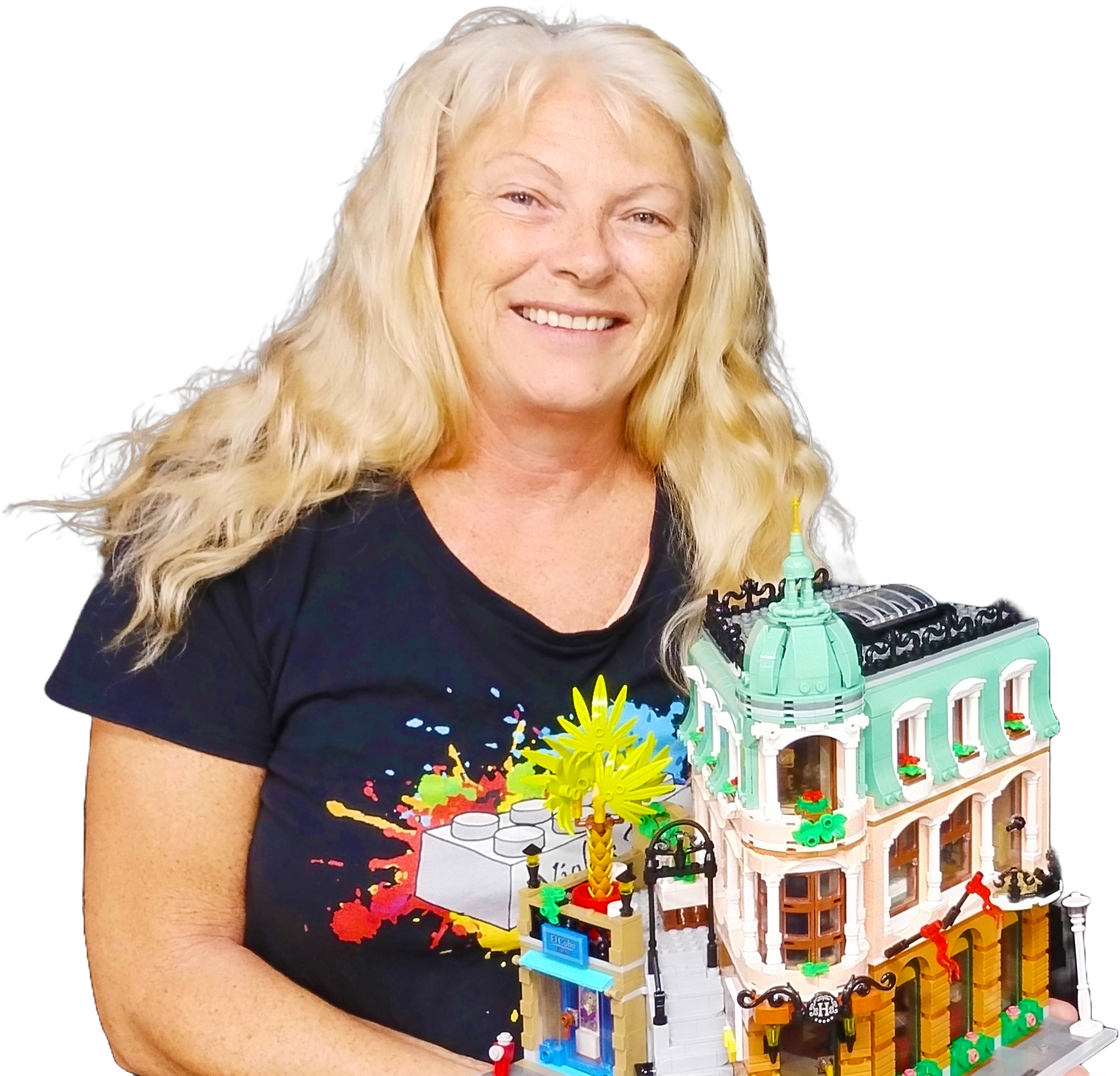 Woman smiling, holding a Lego building model with details in green, tan, and brown.