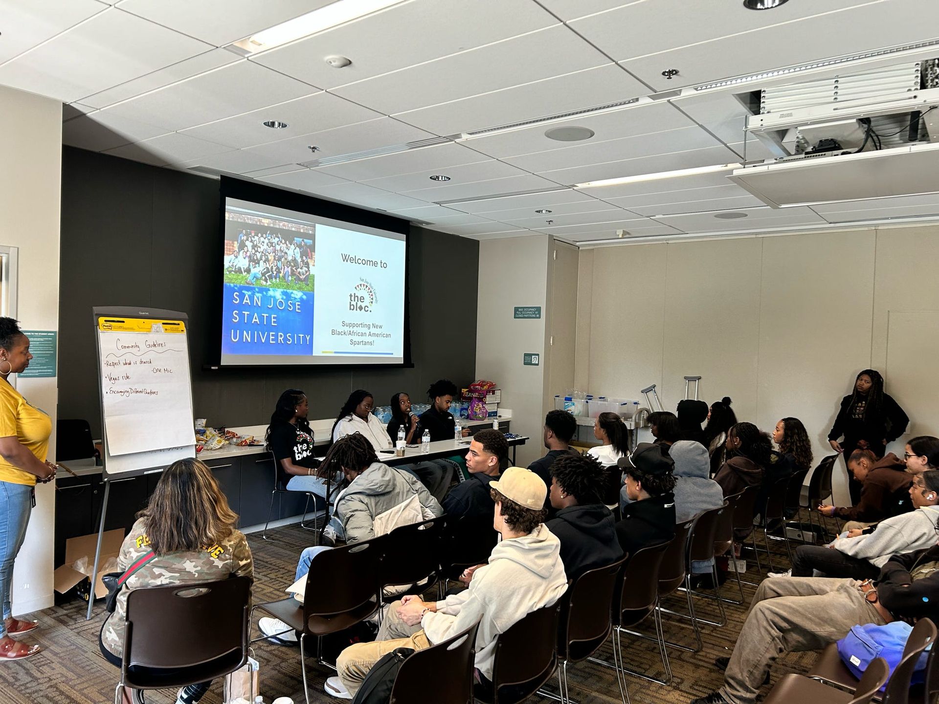 A group of people are posing for a picture in front of a projector screen.
