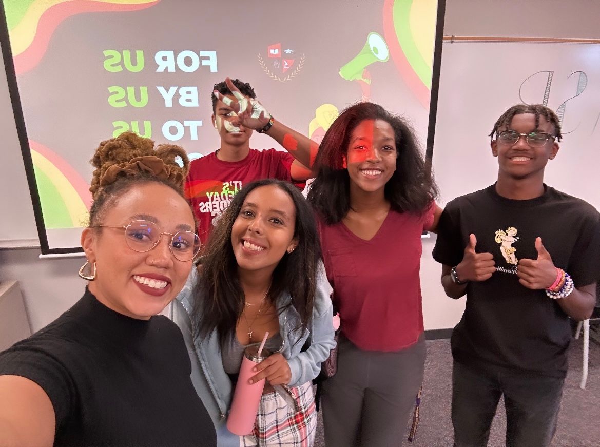 A group of people are posing for a picture in a classroom.