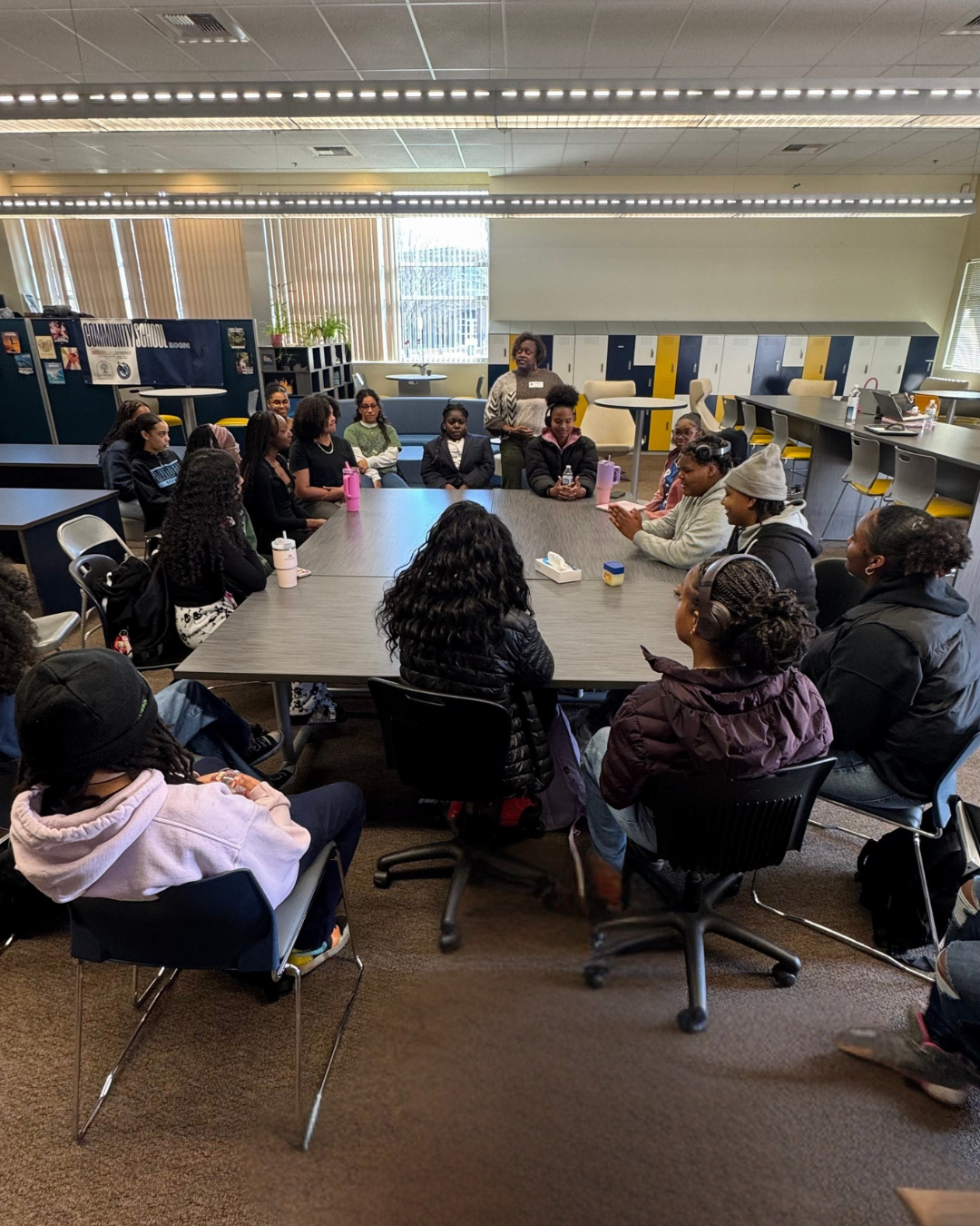 A group of students are standing in a circle in a classroom.