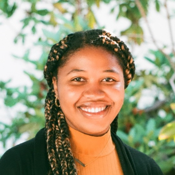 A woman with braids smiling and wearing a black blazer
