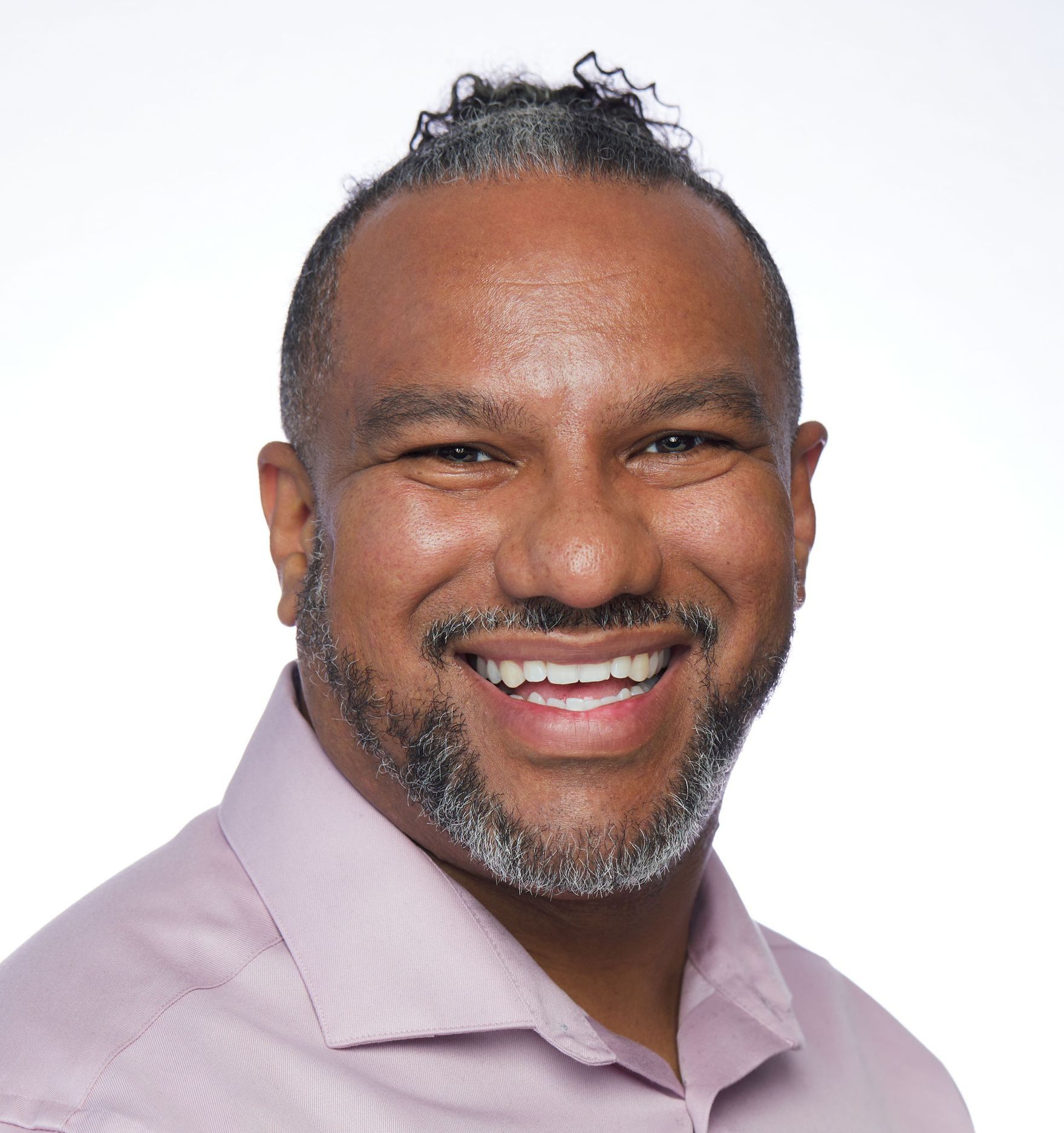 A man wearing a light purple shirt smiling at the camera