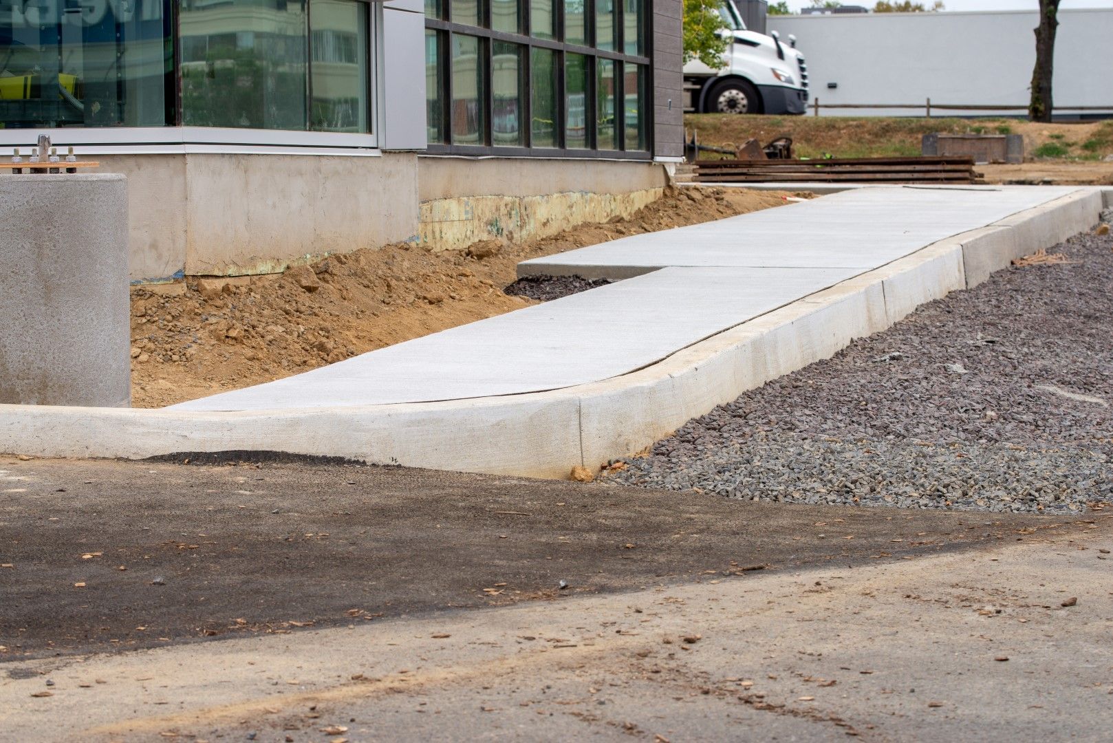 Concrete ramp leading to a building entrance; gravel and dirt alongside.