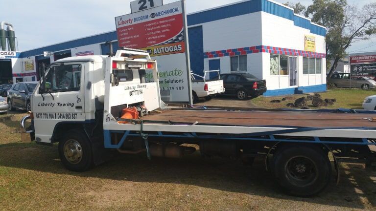 A Tow Truck is Parked in Front of a Building — Mechanical Servicesin Maroochydore, QLD