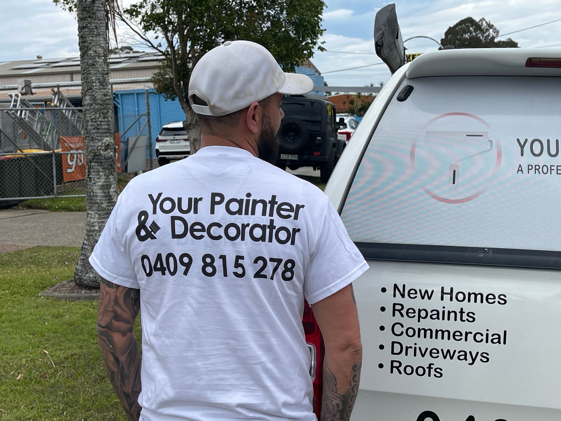 Man wearing a shirt with painting business info stands next to a van with business details. — Carbon Copy Digital in Wauchope, NSW