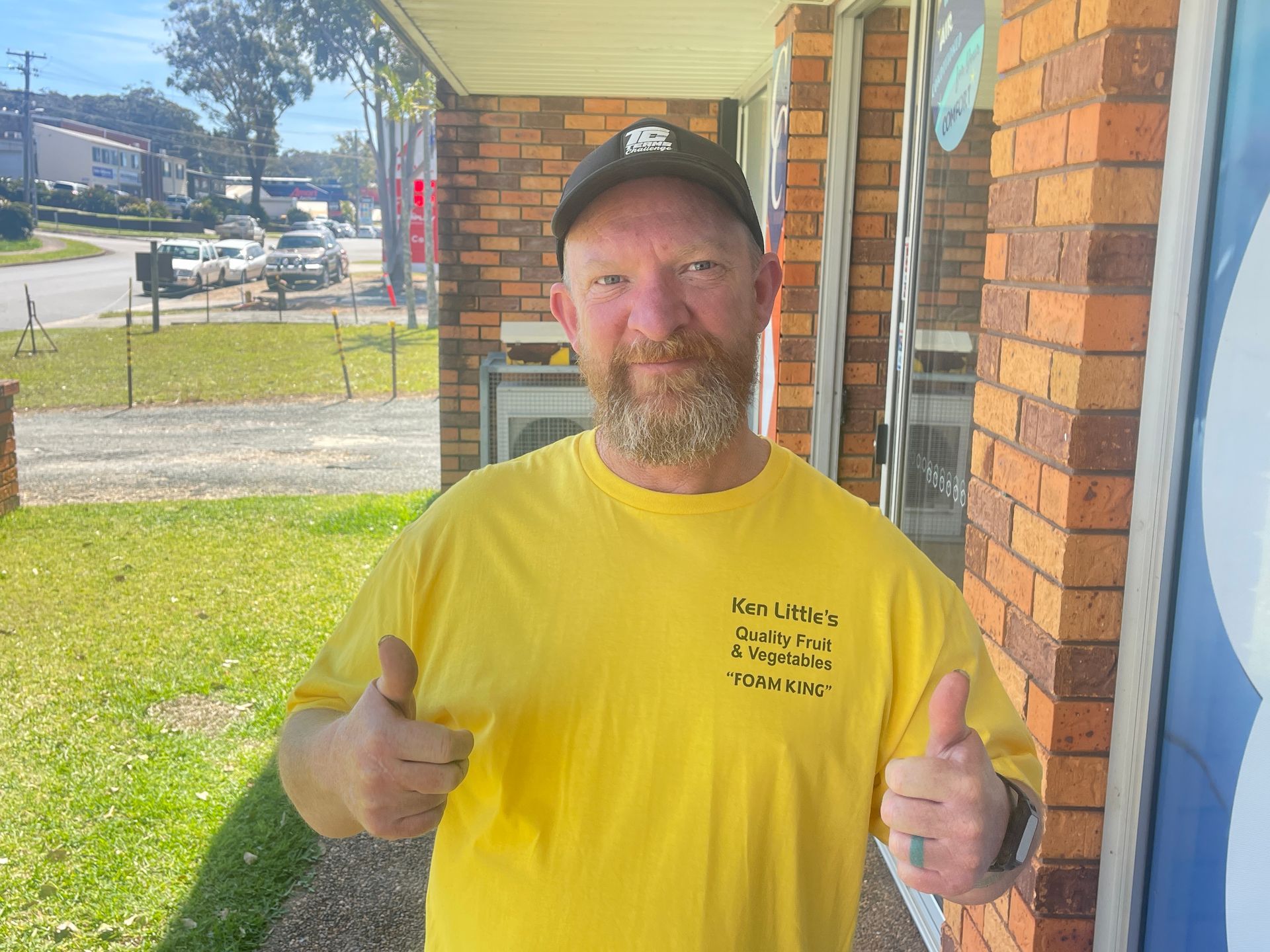 Man in yellow shirt gives thumbs up outside a brick building with a business sign — Carbon Copy in Port Macquarie, NSW