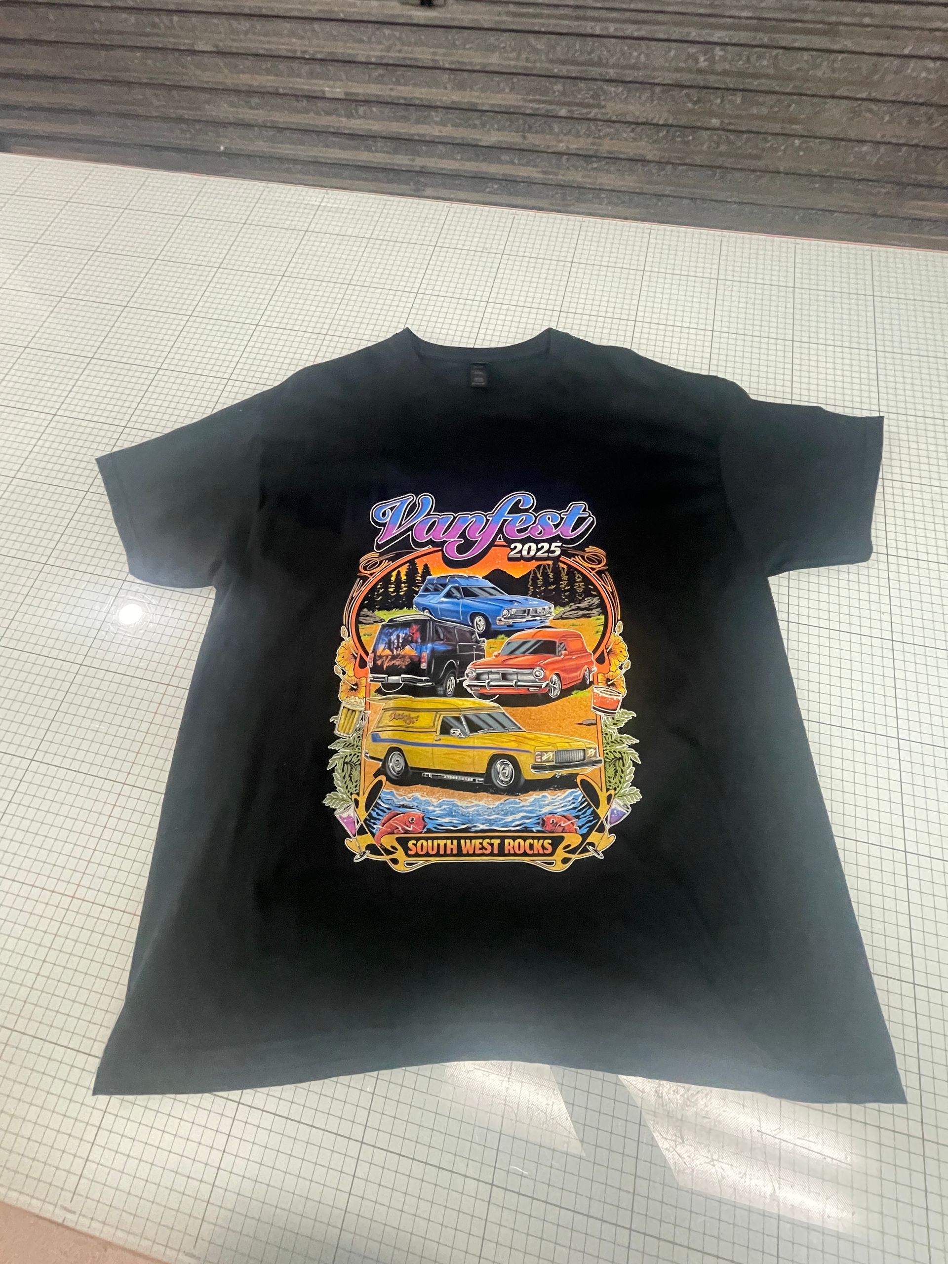 Black t-shirt with a colorful car graphic: Los Angeles scene with vintage vehicles, palm trees, and floral borders. — Carbon Copy Digital in Kempsey, NSW