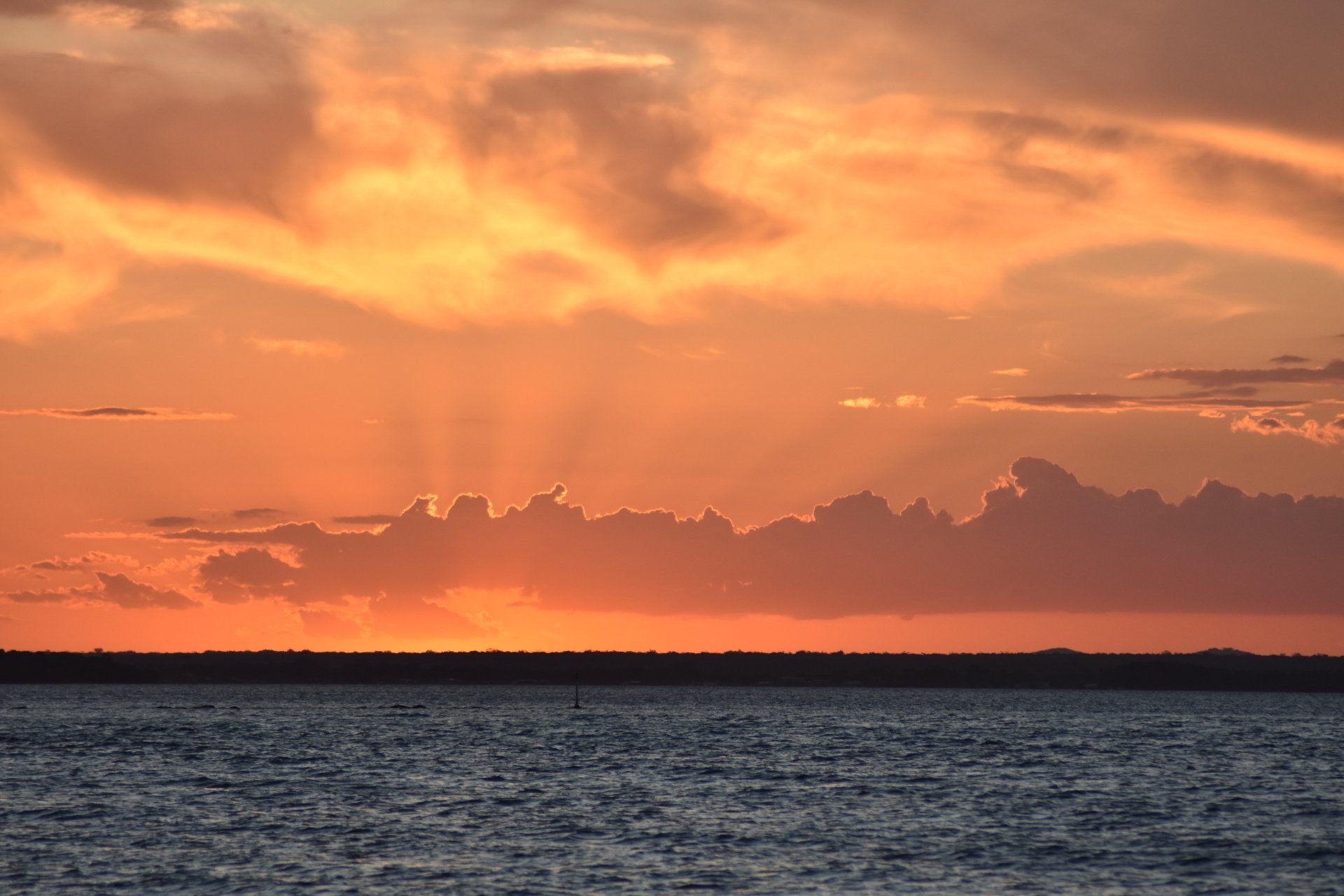 The sun is shining through the clouds over the ocean at sunset.