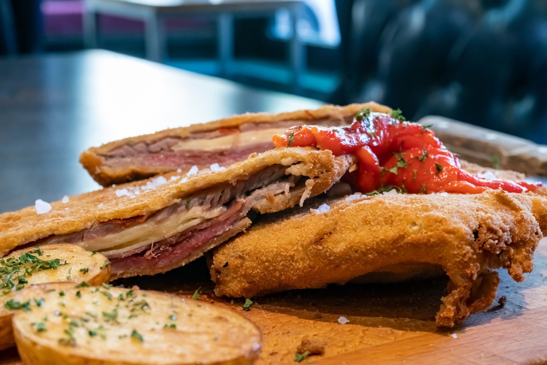A close up of a sandwich on a wooden cutting board on a table.