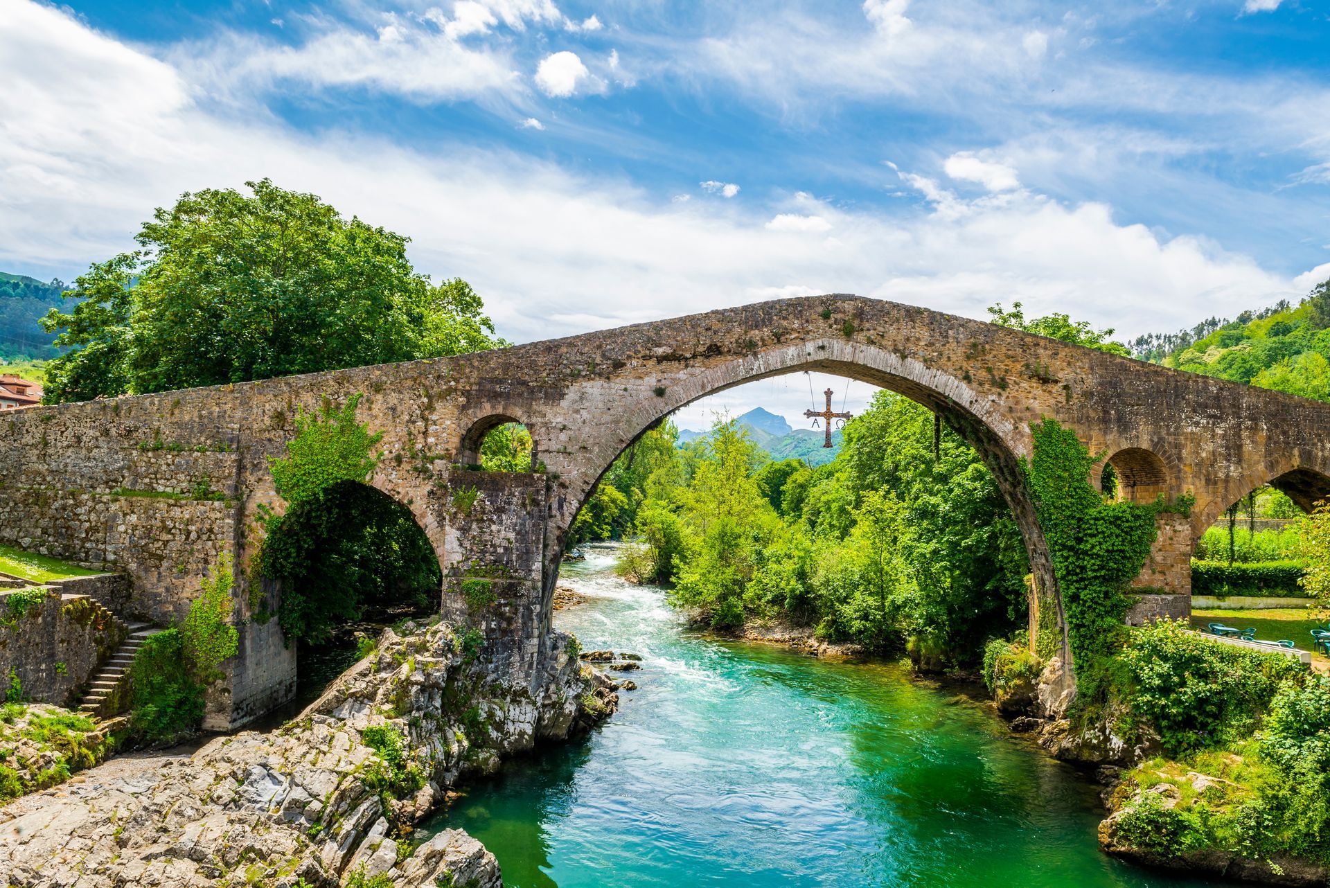 A stone bridge over a river surrounded by trees.