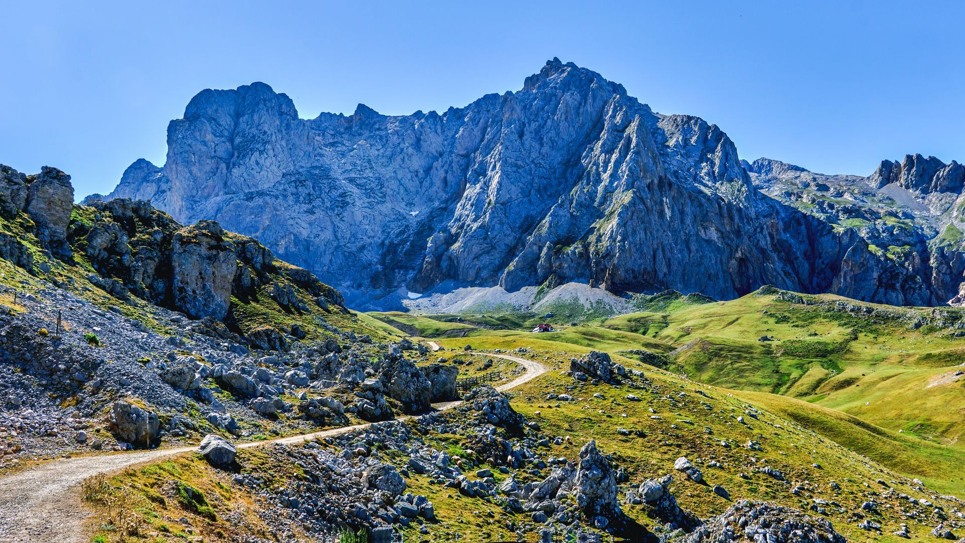 A dirt road in the mountains with a mountain in the background.