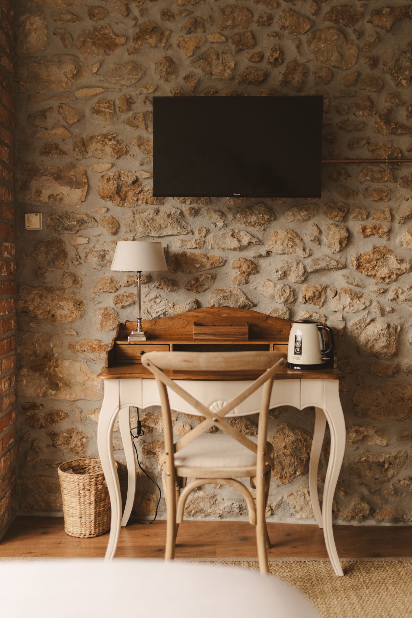 There is a desk with a chair and a television on the wall.