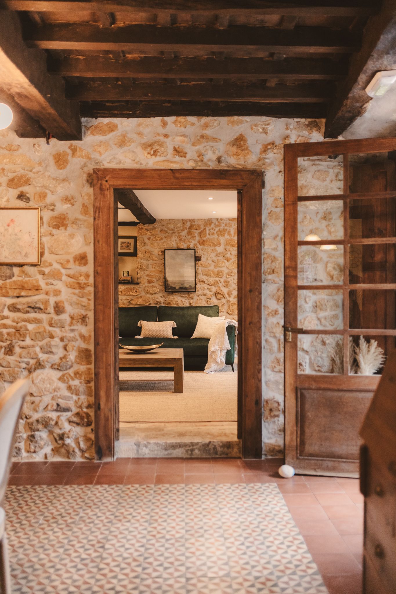 A doorway leading into a living room with a stone wall and wooden beams.