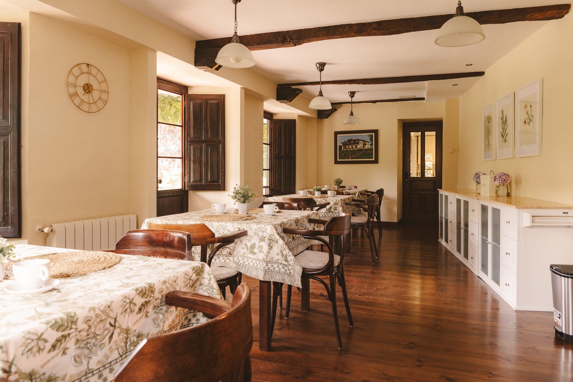 A dining room with tables and chairs and a clock on the wall.