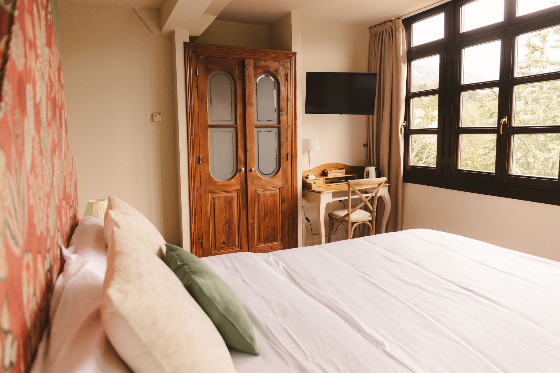 A bedroom with a bed , desk , wardrobe and windows.