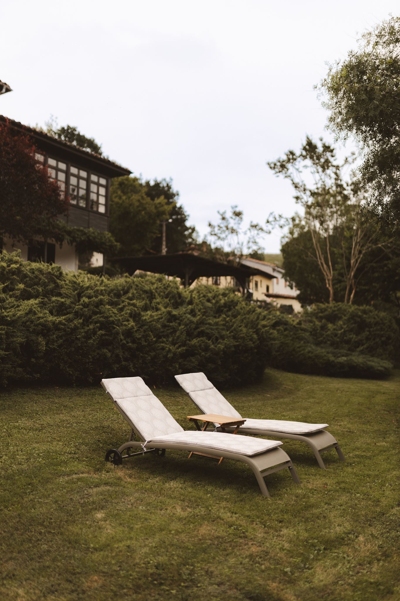 Two lounge chairs are sitting in the grass in front of a house.