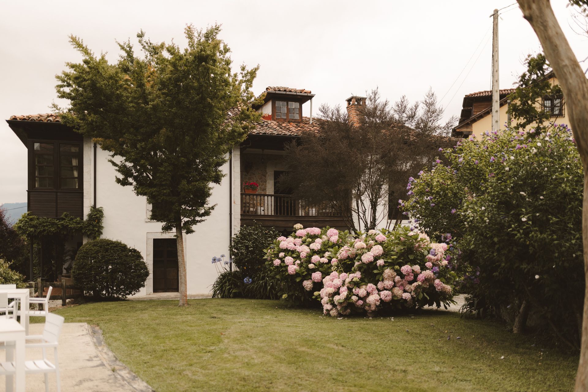 A large white house is surrounded by trees and bushes