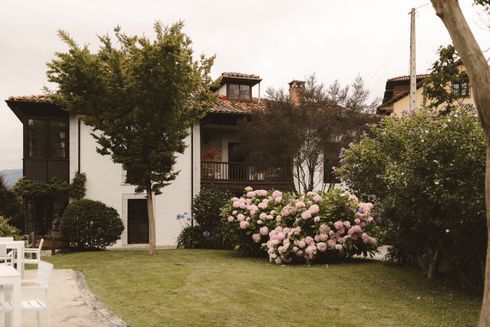 A large white house is surrounded by trees and bushes
